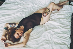 Helena on her back on a bed in black semi-transparent body